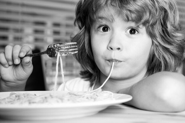 Bambino divertente che mangia pasta spaghetti faccia primo piano ritratto della testa dei bambini