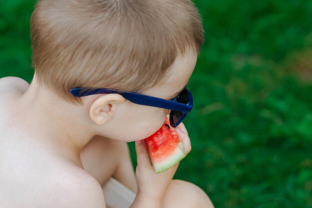 재미있는 아이는 여름 정원에서 야외에서 수박을 먹습니다 아기 아기 건강 식품