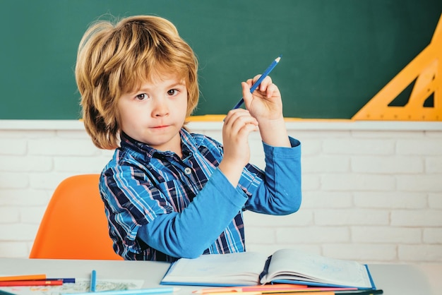 Foto il bambino divertente dei bambini della scuola elementare contro il bambino della lavagna verde si prepara per la scuola