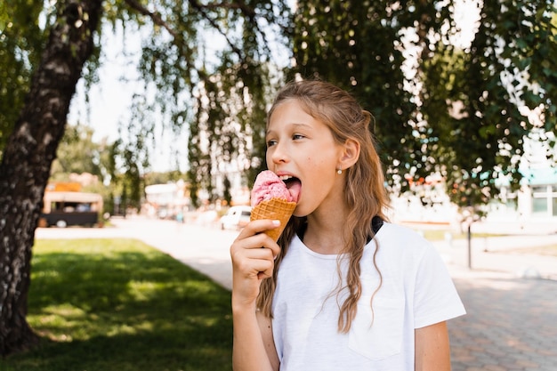 Funny child girl eating ice cream cone in waffle cup Creative advert for ice cream stand and shop