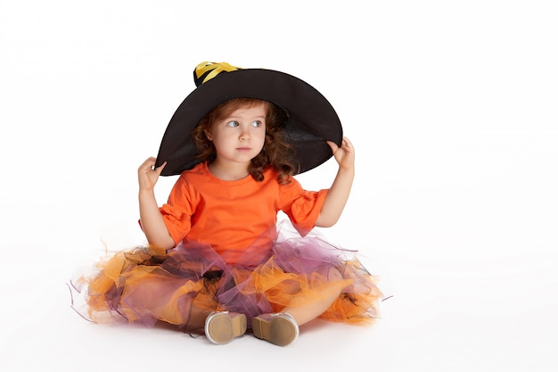 Funny child girl in witch costume for Halloween on white