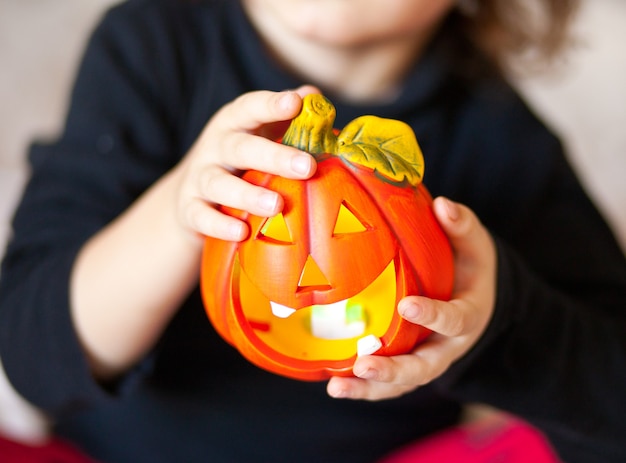 Funny child girl in witch costume for Halloween with pumpkin Jack in a hands