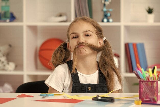 Funny child having fun with long hair pony tail at school lesson in classroom wear uniform fun