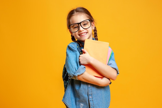 Фото Забавная девочка-школьница на желтом фоне