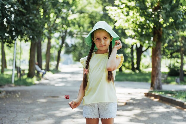 Funny child with candy lollipop, happy little girl eating big