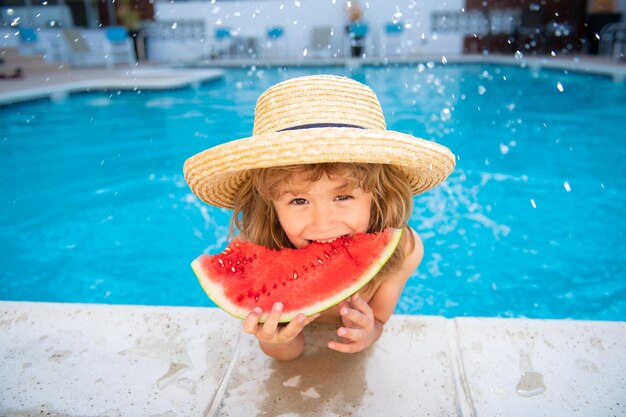 Funny child with watermelon kid having fun in swimming pool summer vacation and healthy eating