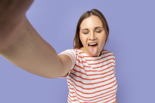 전면 자화상을 만드는 카메라에 혀를 보여주는 셀카 사진을 찍는 재미있는 유치한 여자