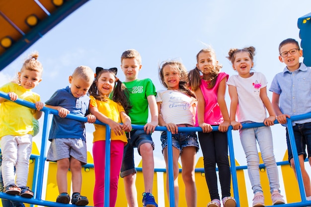 Foto bambini divertenti stanno insieme in un bel parco giochi e guardano la telecamera