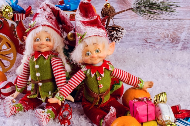 面白いクリスマスエルフは明るい木製の背景にクリスマス靴下の隣に座っています。