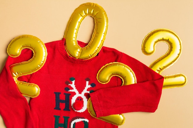 Funny christmas sweater holding  year on beige background flat lay top