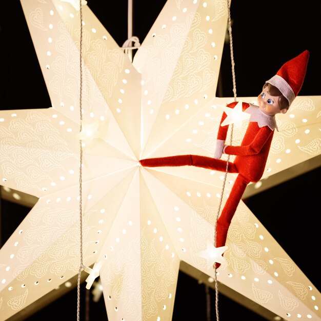 A funny Christmas toy is hanging on a garland against the background of a large paper Christmas star