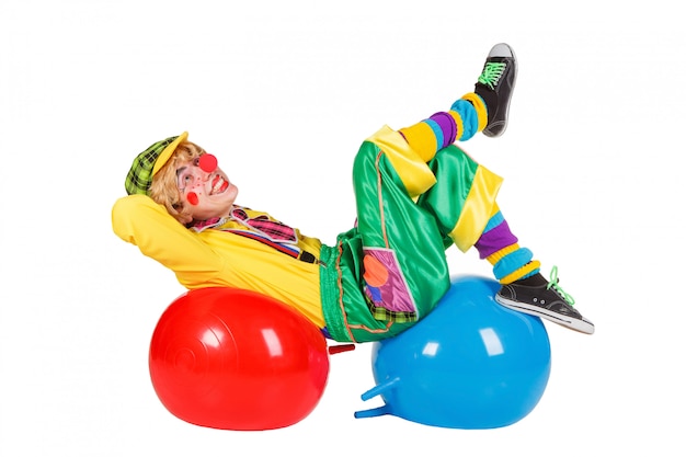 Funny clown lies on balls isolated on white background