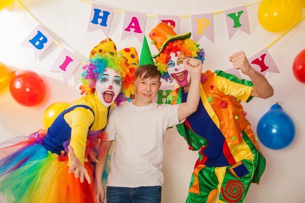 Funny clowns at the holiday show their good emotions with a\
boy