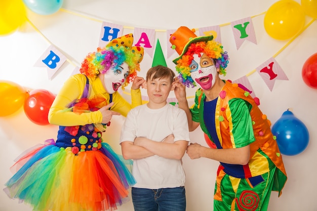 Funny clowns at the holiday show their good emotions with a boy