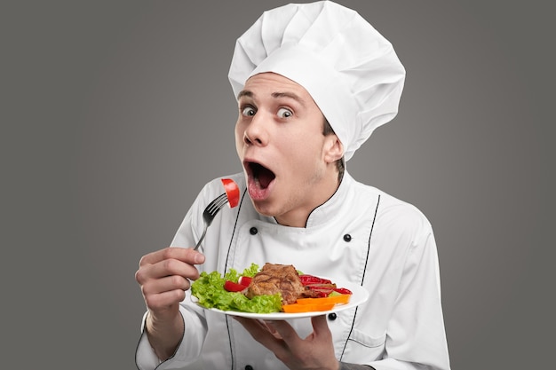 Funny cook eating salad in studio