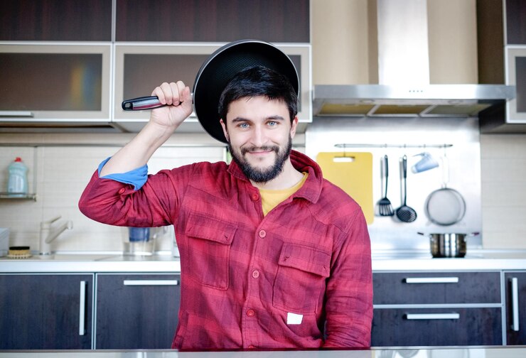 फोटो funny cooking attractive caucasian man in the kitchen with dripping pan on his head
