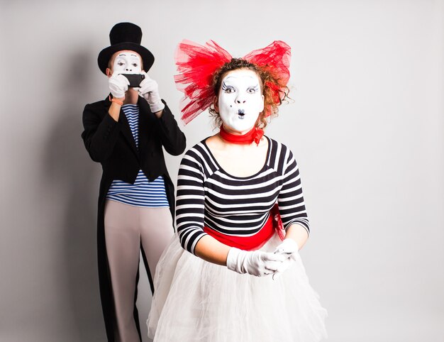 Funny couple of mimes taking a selfie photo on a mobile phone. Concept of April Fools Day