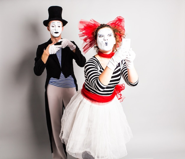 Funny couple of mimes taking a selfie photo on a mobile phone. Concept of April Fools Day