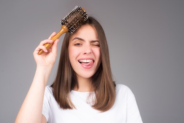 Funny crazy woman combing hair portrait of female model with tongue combing brushing hair girl with