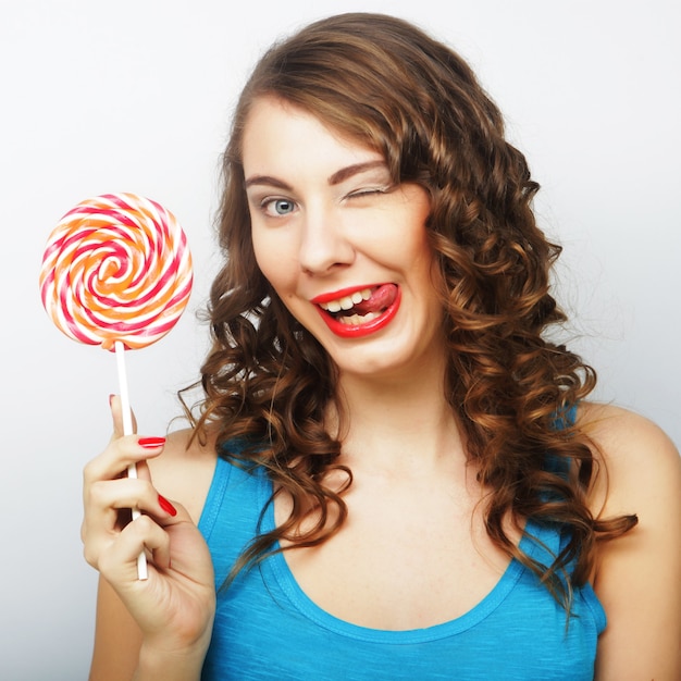 Funny curly woman holding big lollipop. Birthday party.