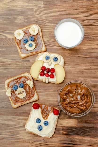 Funny cute bearmonkeyfoxowl faces sandwich toast bread with\
peanut butterbananablueberryraspberrymilk kids childrens baby\'s\
sweet dessert healthy breakfast lunch food artclose uptop view
