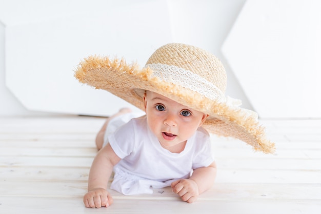 Funny cute child girl 3-4 year old holding straw hat wearing white top and denim shorts posing in park. Happiness. Summer season.