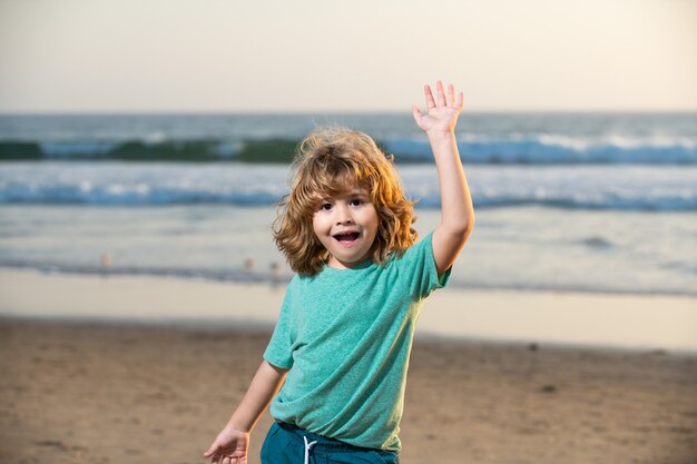 海のビーチを歩く面白いかわいい子供の男の子