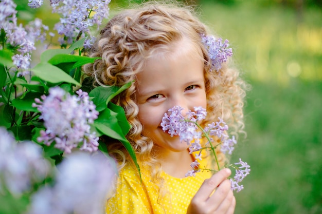 Funny cute laughing little girl in spring in a blooming lilac garden