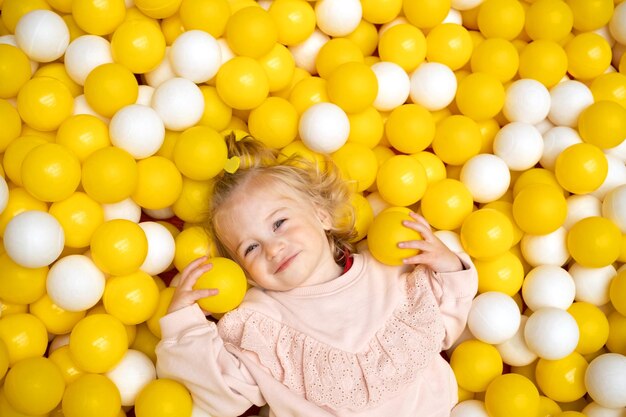 Funny cute little caucaisian blonde baby girltoddler smiling happy kid having fun in ball pool