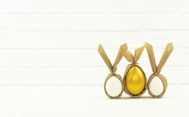 Funny decorated and painted golden eggs stand on a white table in the kitchen