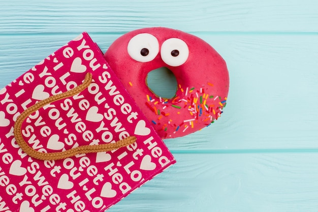 Funny donut and shopping bag on wooden background.