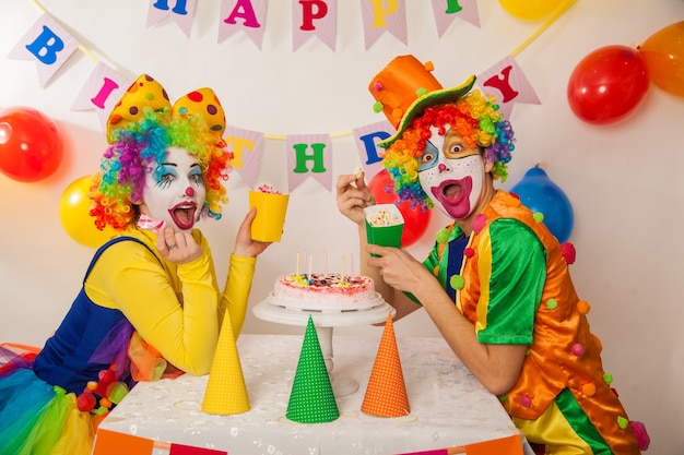 Funny emotional clowns at the party cannot share the cake