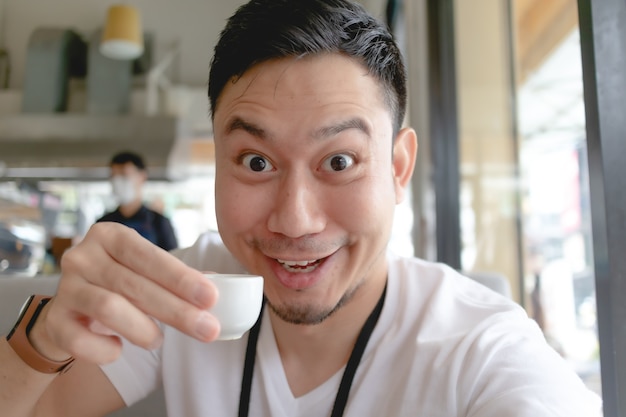 Funny face of Asian man eat and drink in a cafe.