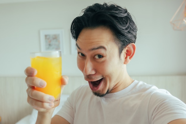 Funny face of man drink fresh orange juice in the hotel for summer vacation