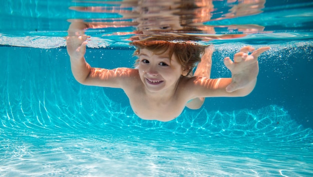 Funny face portrait of child boy swimming and diving underwater with fun in pool