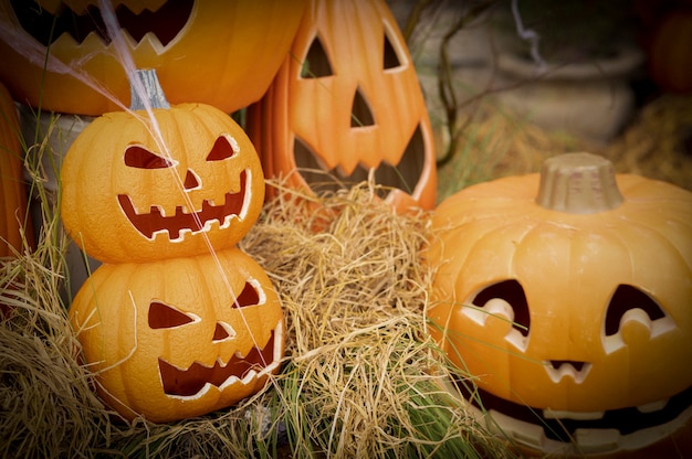 Funny face pumpkin on straw in grunge Halloween background.