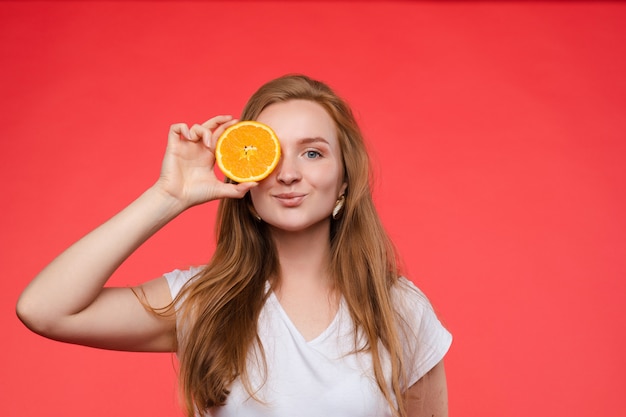 Photo funny fashionable woman with hairstyle holding oranges on eyes