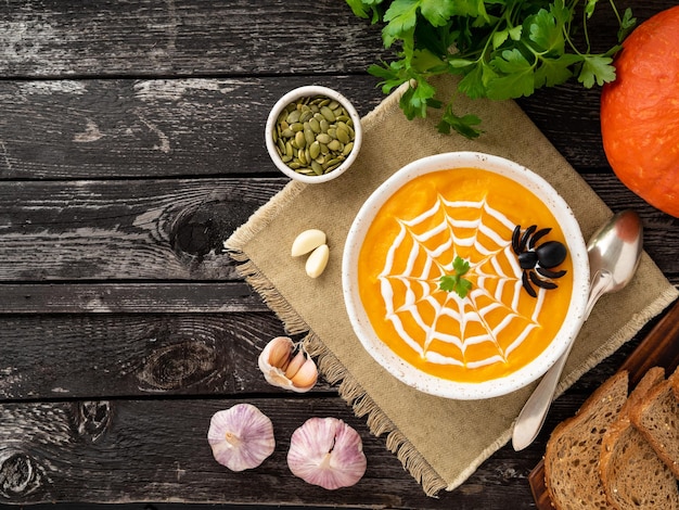 Photo funny food for halloween pumpkin puree soup spider web dark old wooden table top view copy space