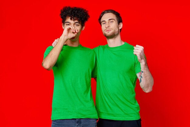 Funny friends green tshirts hugs emotions joy red background high quality photo