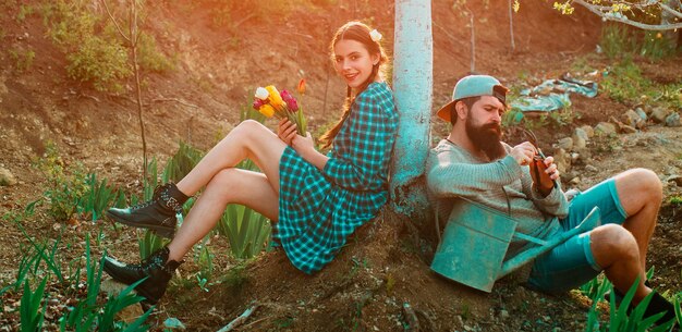 Funny gardener couple holding garden tools at spring nature background teamwork and friends together