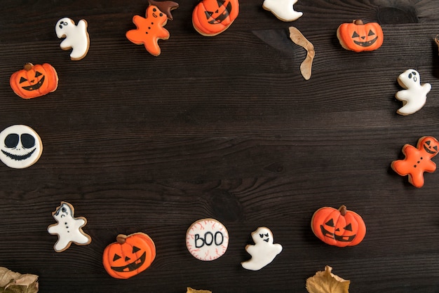 Прикольное имбирное печенье на Хэллоуин на столе в виде тыквы, привидения и смайлика. Вид сверху. Место для текста