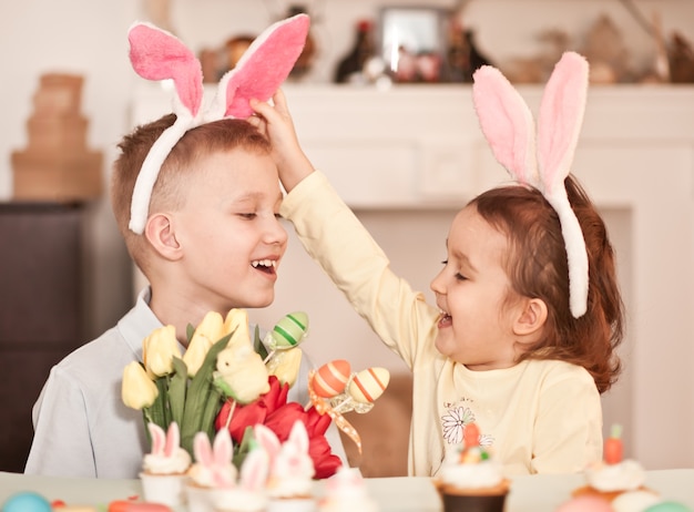 Funny girl and boy child wearing bunny ears in spring time at home.