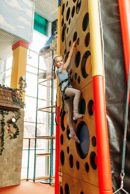 Foto ragazza divertente arrampicata su pareti nel centro giochi per bambini