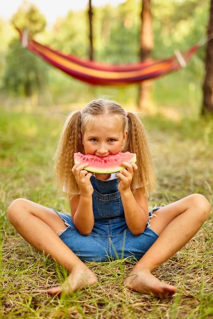 Ragazza divertente che mangia anguria nel parco