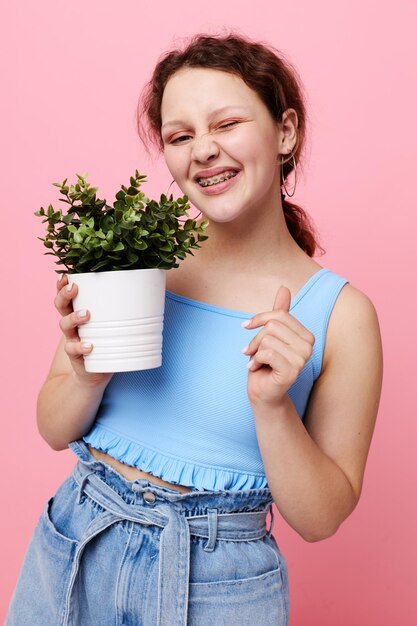 白いポットの面白い女の子の花は、感情の孤立した背景を変更せずにポーズをとる