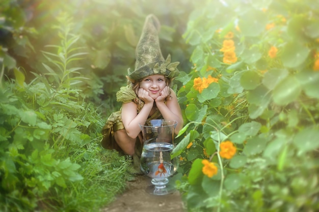 Funny girl in a gnome hat and a suit in a green garden.