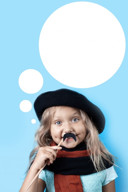 Фото Смешная девчонка в черном берете, шарфе и усах на палочке на синем фоне
