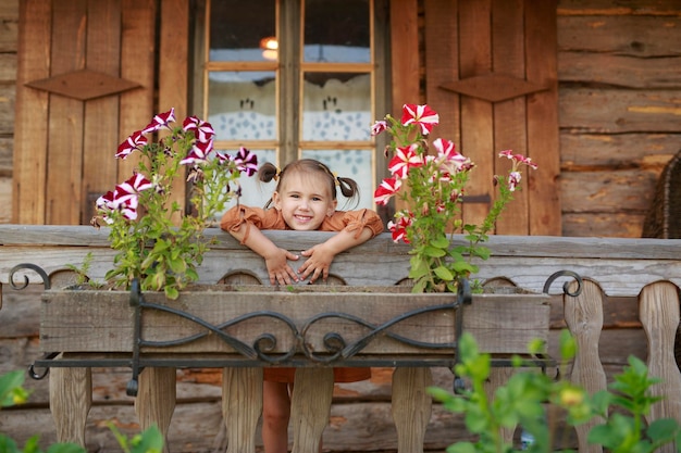 Funny girl is standing on balcony of an old wooden village house