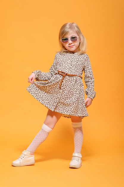 Funny girl in leopard dress and glasses on yellow posing