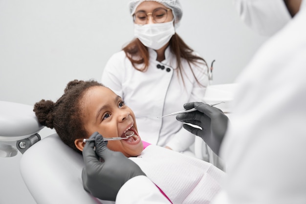 写真 口を開けて歯科医の椅子に横たわっている面白い女の子